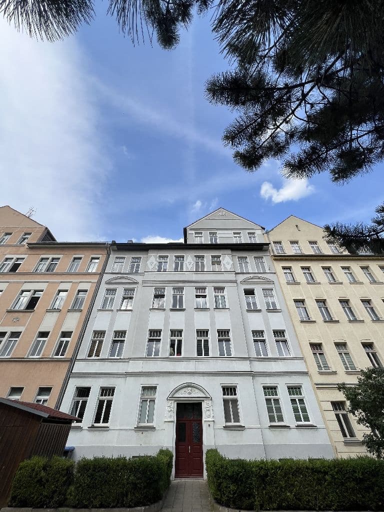 Fünfgeschossiges Wohnhaus mit Satteldach und weißer Fassade, rote Eingangstür, Gotzkowskystraße in Leipzig-Neulindenau
