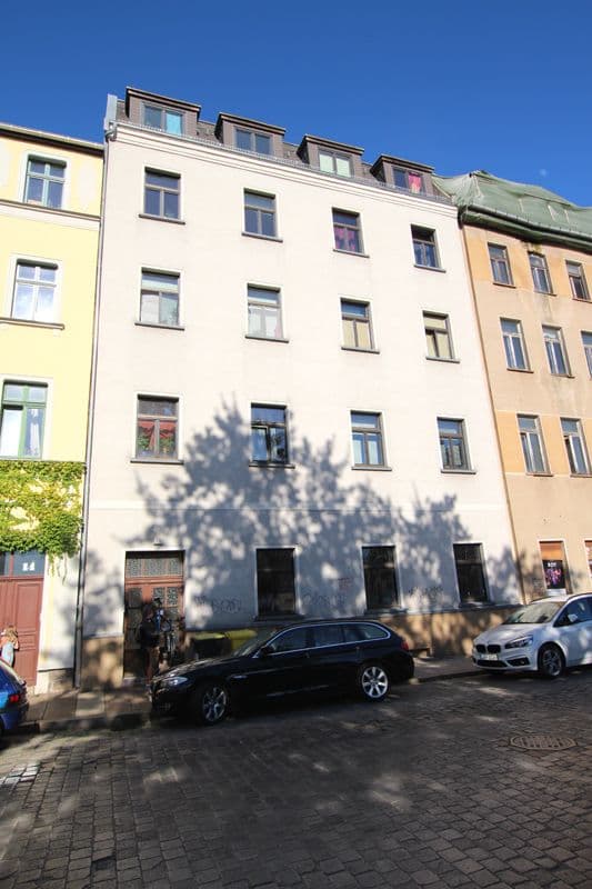 Fünfgeschossiges Wohnhaus mit Mansardendach, heller Fassade, regelmäßigen Fensterreihen, Hans-Poeche-Straße in Leipzig