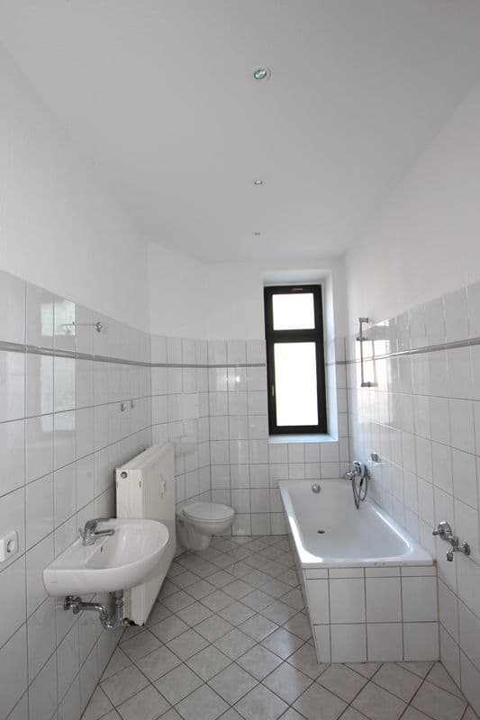 Badezimmer mit weißen Wandfliesen, Wanne, Bidet und Waschbecken, Fenster mit schwarzem Rahmen