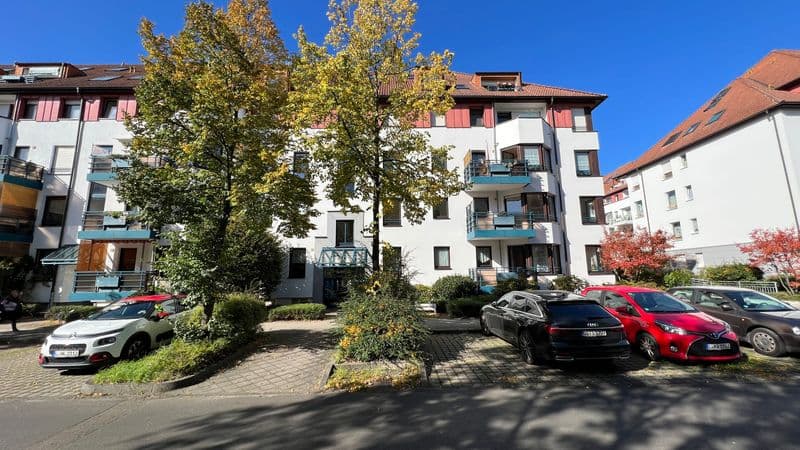 Mehrgeschossiges Wohnhaus mit weißer Fassade, roten Dachziegeln und blauen Balkonen, Hermelinstraße in Leipzig-Paunsdorf
