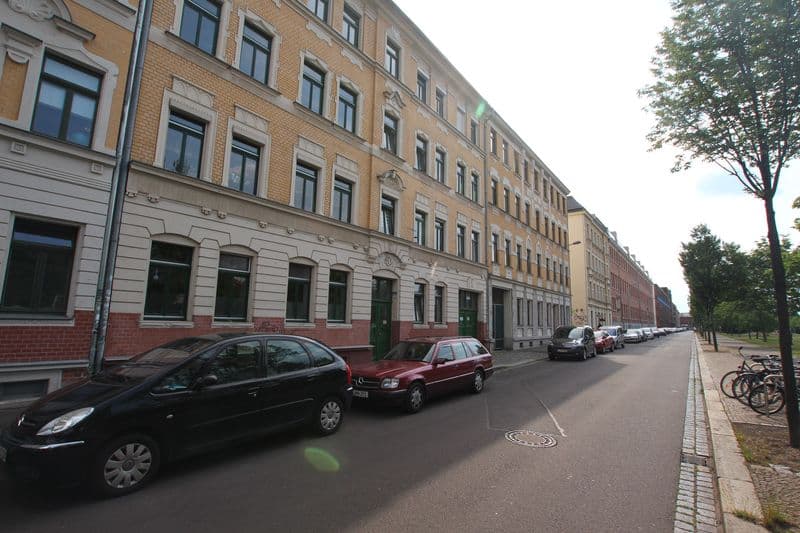 Gründerzeithaus mit vier Geschossen, Ziegelfassade ocker und rot, regelmäßige Fensterreihen, Industriestraße in Leipzig