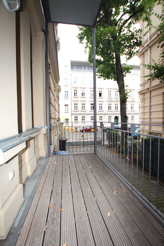 Balkon mit Holzdielen und Metallgeländer, Blick auf Gründerzeithaus und Hofplatz