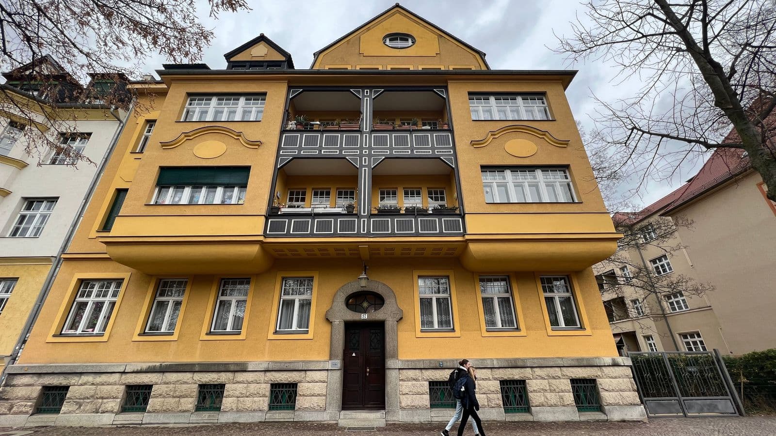 Vier-Geschoss-Wohnhaus mit gelber Fassade, Gründerzeitfassade mit Bossenwerk im Sockelgeschoss, Mansardendach