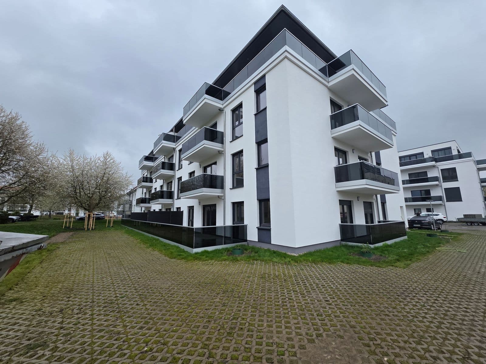 Modernes viergeschossiges Wohngebäude mit weißer Fassade, schwarzen Akzenten und Balkonen, Rotdornstraße in Leipzig-Paunsdorf