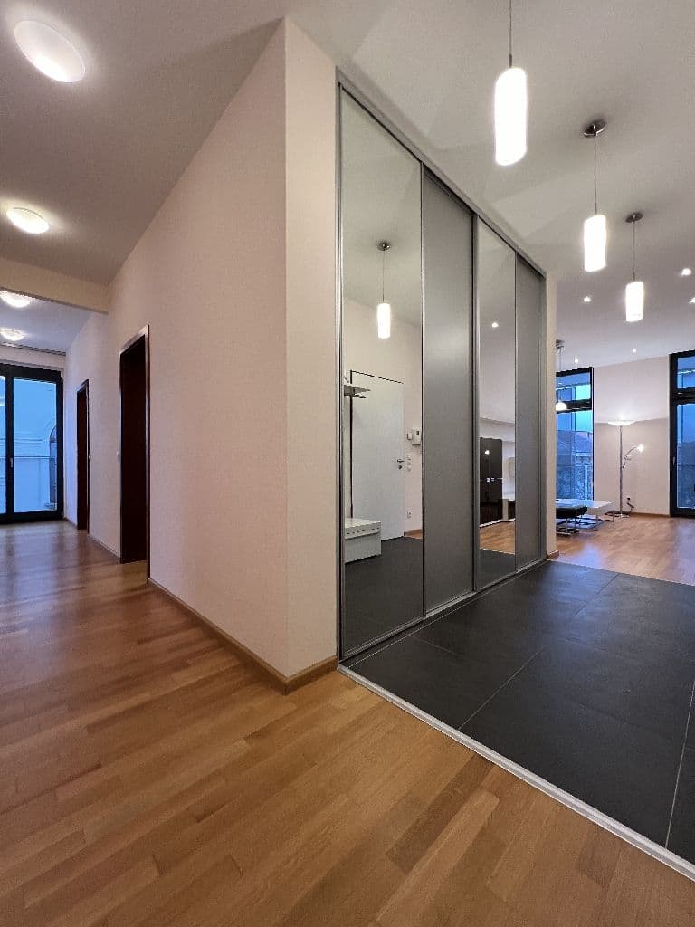 Moderner Flur mit Holzparkett, zentraler Trennwand mit Spiegeltüren, LED-Pendelleuchten