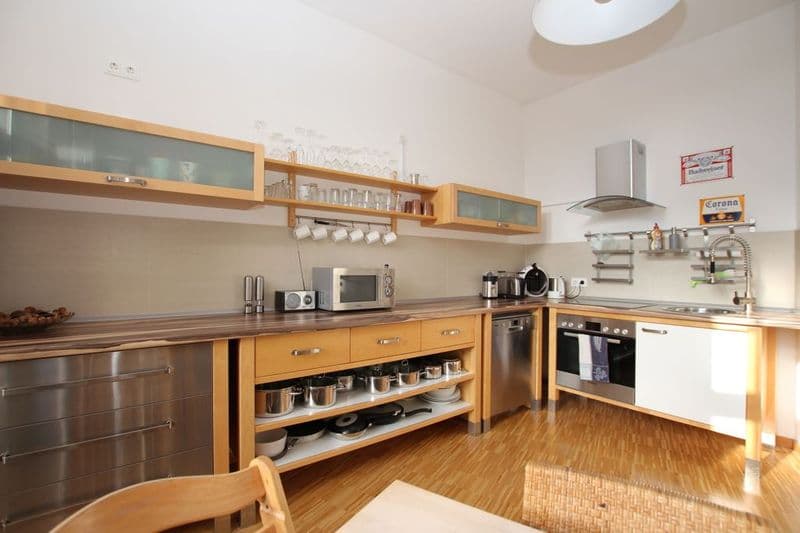 Offene Küche mit Holzfront und Glaselementen, Holzparkett, Edelstahlgeräte, runde Deckenleuchte