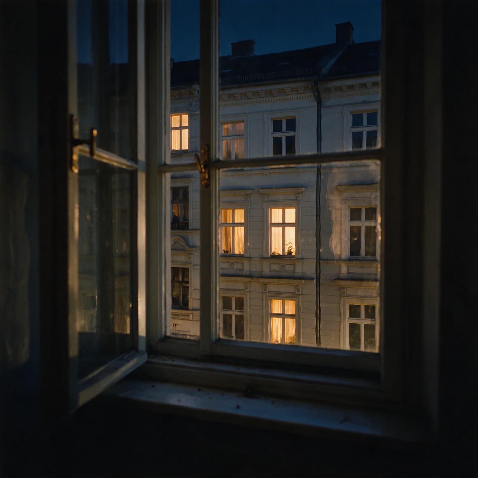 Blick aus dem Fenster einer leeren Altbauwohnung auf die Gründerzeit-Fassaden gegenüber zur blauen Stunde