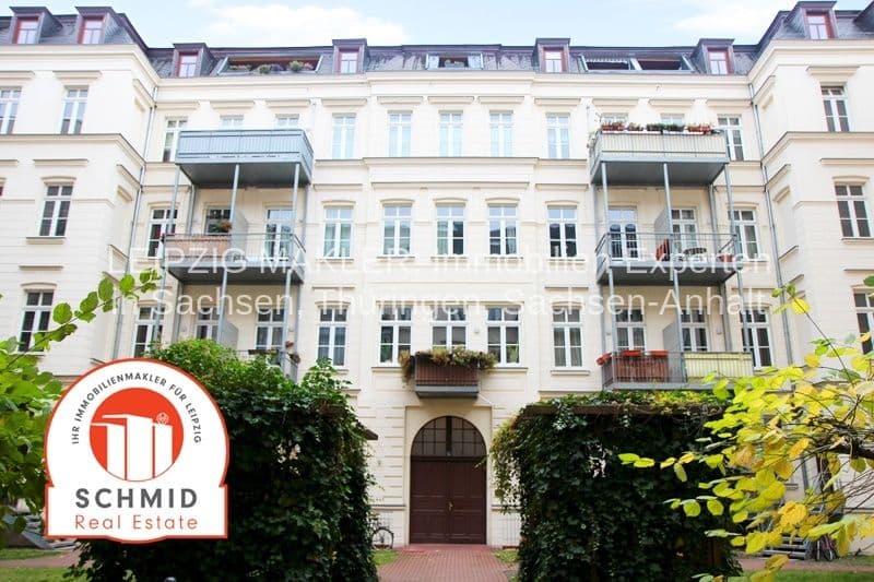 Gründerzeitfassade, vier Geschosse, Mansardendach, moderne Balkone, Eingang mit Rundbogen, grüner Bewuchs
