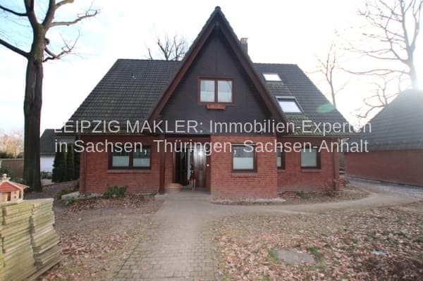 Zweigeschossiges Einfamilienhaus mit Satteldach, Ziegelfassade rot-braun, Dachgauben, Klinkersockel, Kiesauffahrt