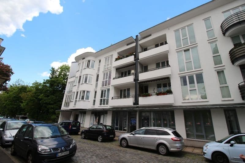 Viergeschossiges Wohnhaus mit weißer Fassade, Balkonen und Einzelhandelsflächen im Erdgeschoss, Chopinstraße in Leipzig