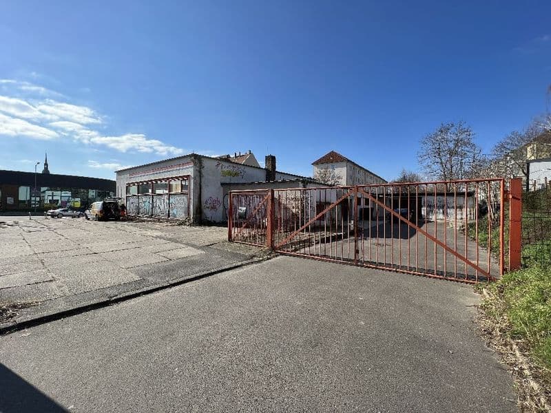 Gewerbefläche mit verfallenen einstöckigen Gebäuden, rostigem Metalltor und Betonplatz, Leonhard-Frank-Straße in Leipzig