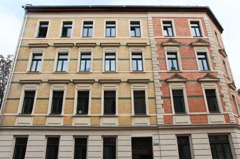 Vierstöckiges Gründerzeithaus mit Ziegelfassade in Gelb und Rot, Rechteckfenster mit Sprosseneinteilung