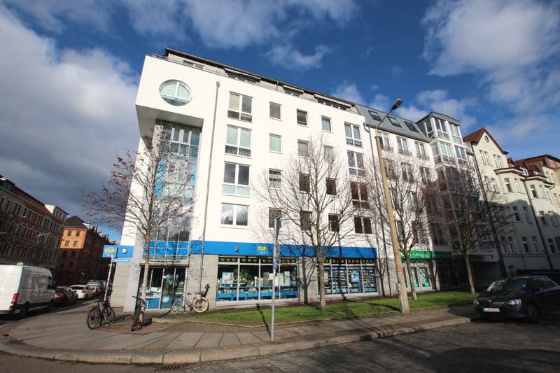 Fünfgeschossiges Wohngebäude mit weißer Fassade, blauem Ladengeschoss und Mansardendach, Riebeckstraße in Leipzig