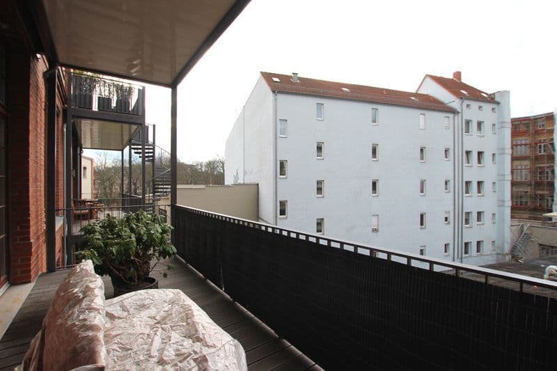 Balkon mit Holzboden, schwarzem Geländer und Blick auf mehrgeschossige Wohngebäude, Spohrstraße in Leipzig