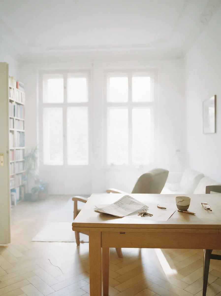 Wohnraum in einem sanierten Gründerzeithaus im Morgenlicht, auf dem Tisch ein Grundriss und Schlüssel