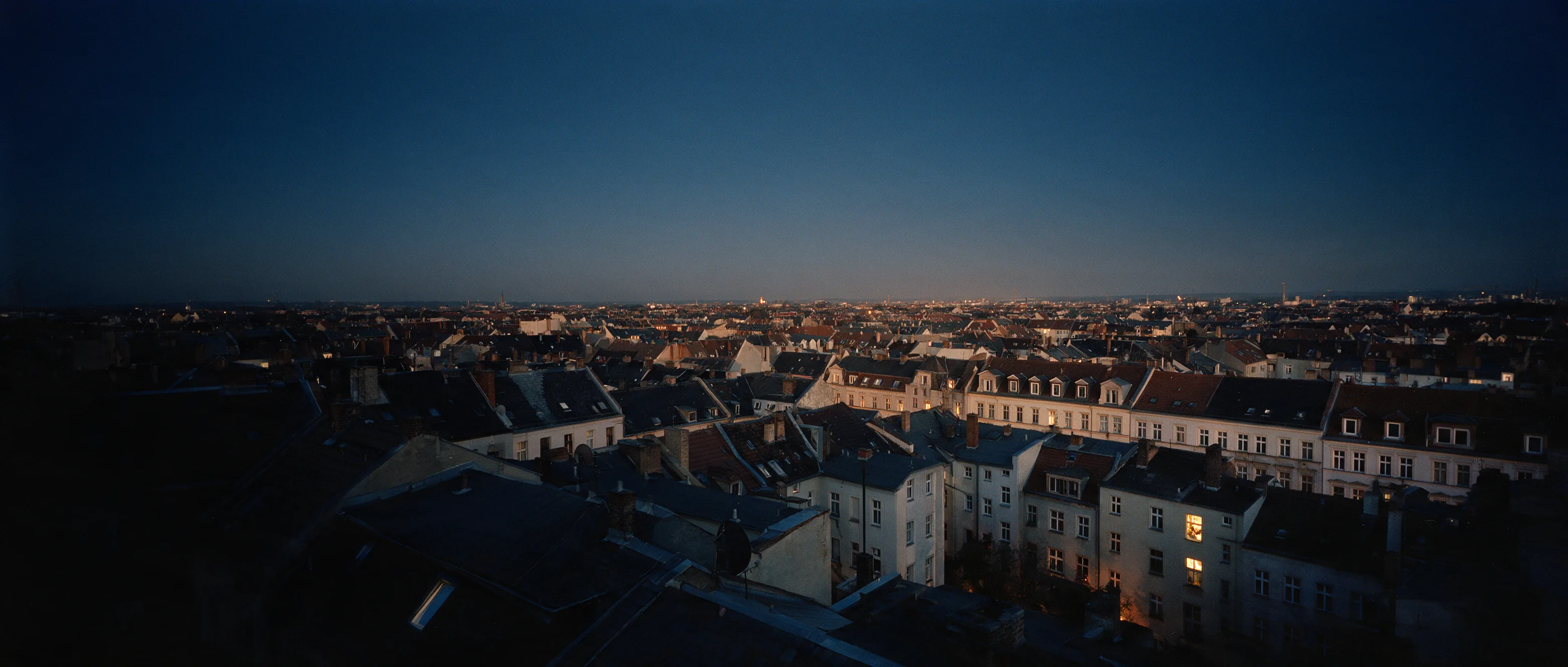 Blick über die Dächer eines Leipziger Gründerzeitviertels zur blauen Stunde